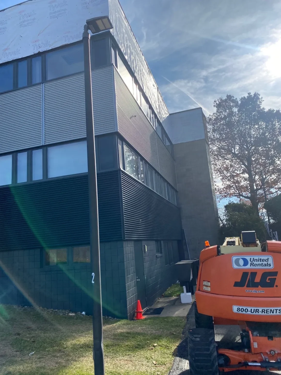 JLG aerial lift alongside commercial building during exterior siding installation