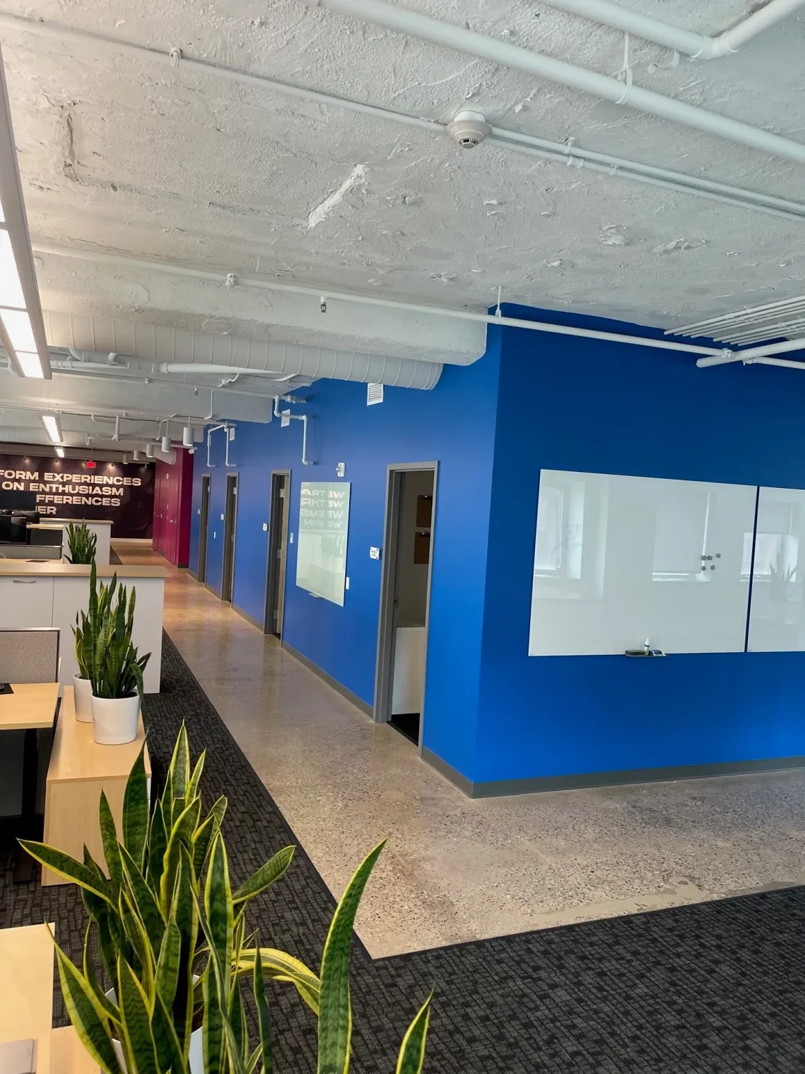 Office lounge area with blue accent wall, mounted TV, and seating