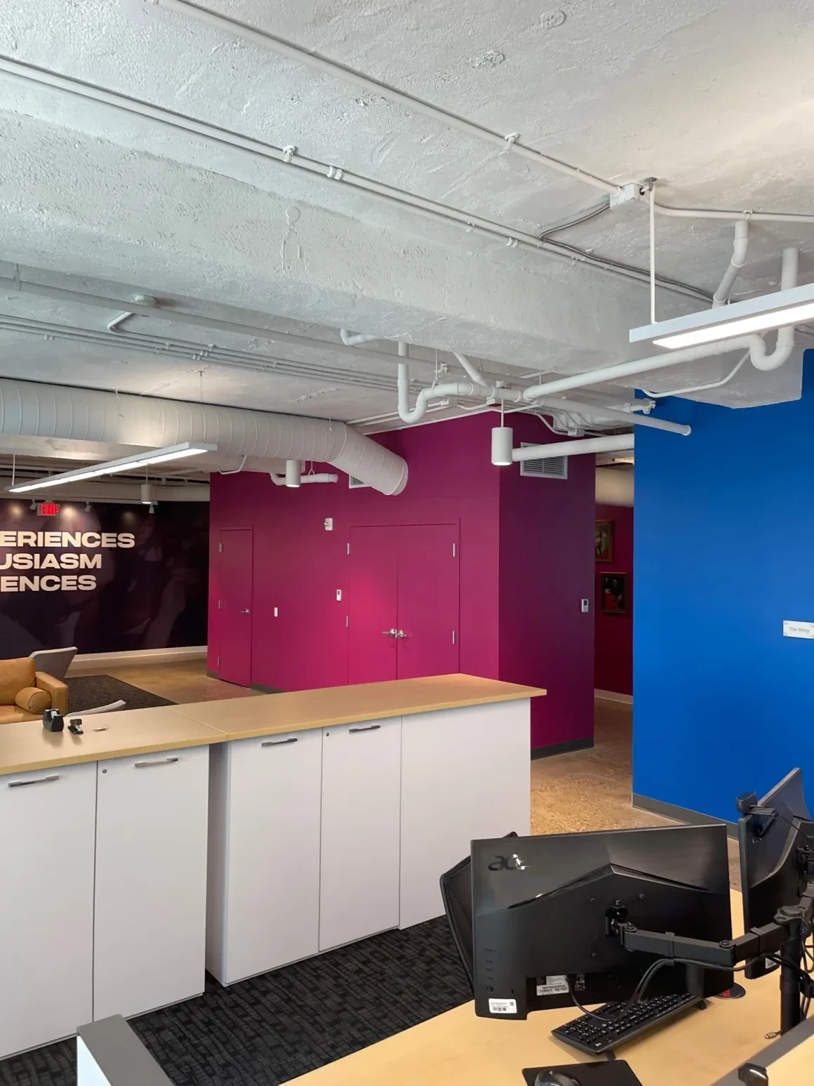 Open office floor with blue accent wall, glass garage doors, and workstations