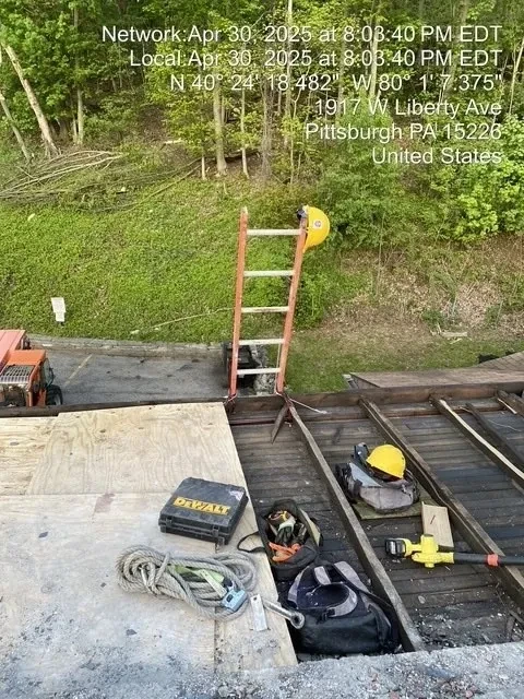 Ladder, DeWalt tools, and safety gear on roof during emergency repair at 1917 W Liberty Ave