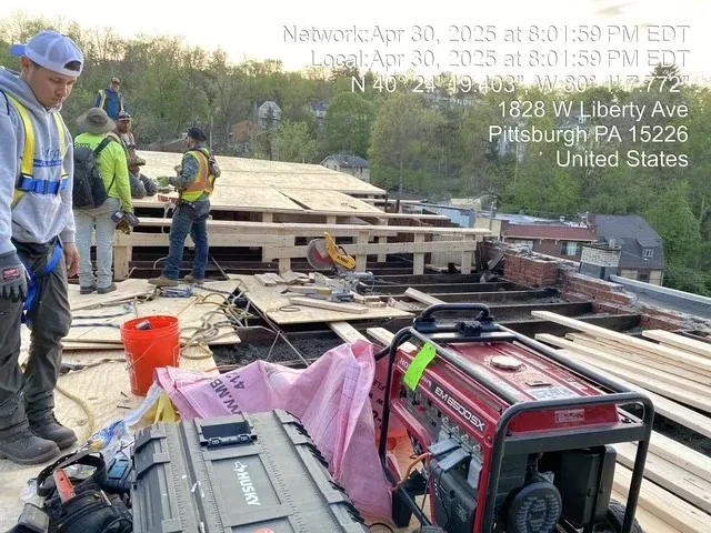 Crew installing new roof decking with generator and insulation on active worksite