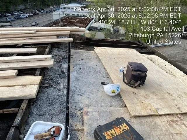Worker laying new plywood decking over exposed roof rafters
