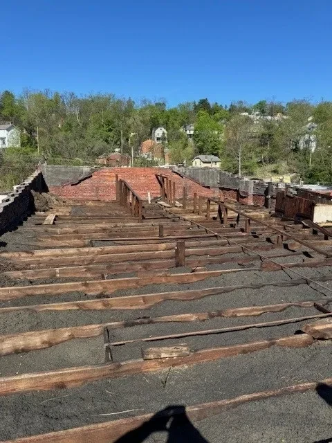 Exposed roof rafters and damaged structure before decking installation