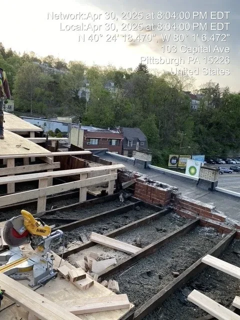 New roof decking partially installed with miter saw and lumber staged on roof