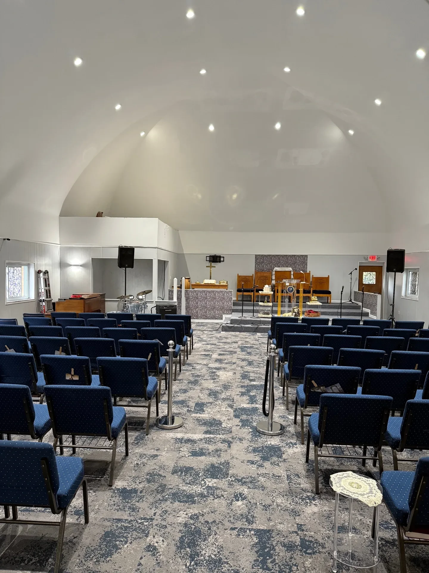 Restored church sanctuary with new vaulted ceiling, recessed lighting, and blue seating