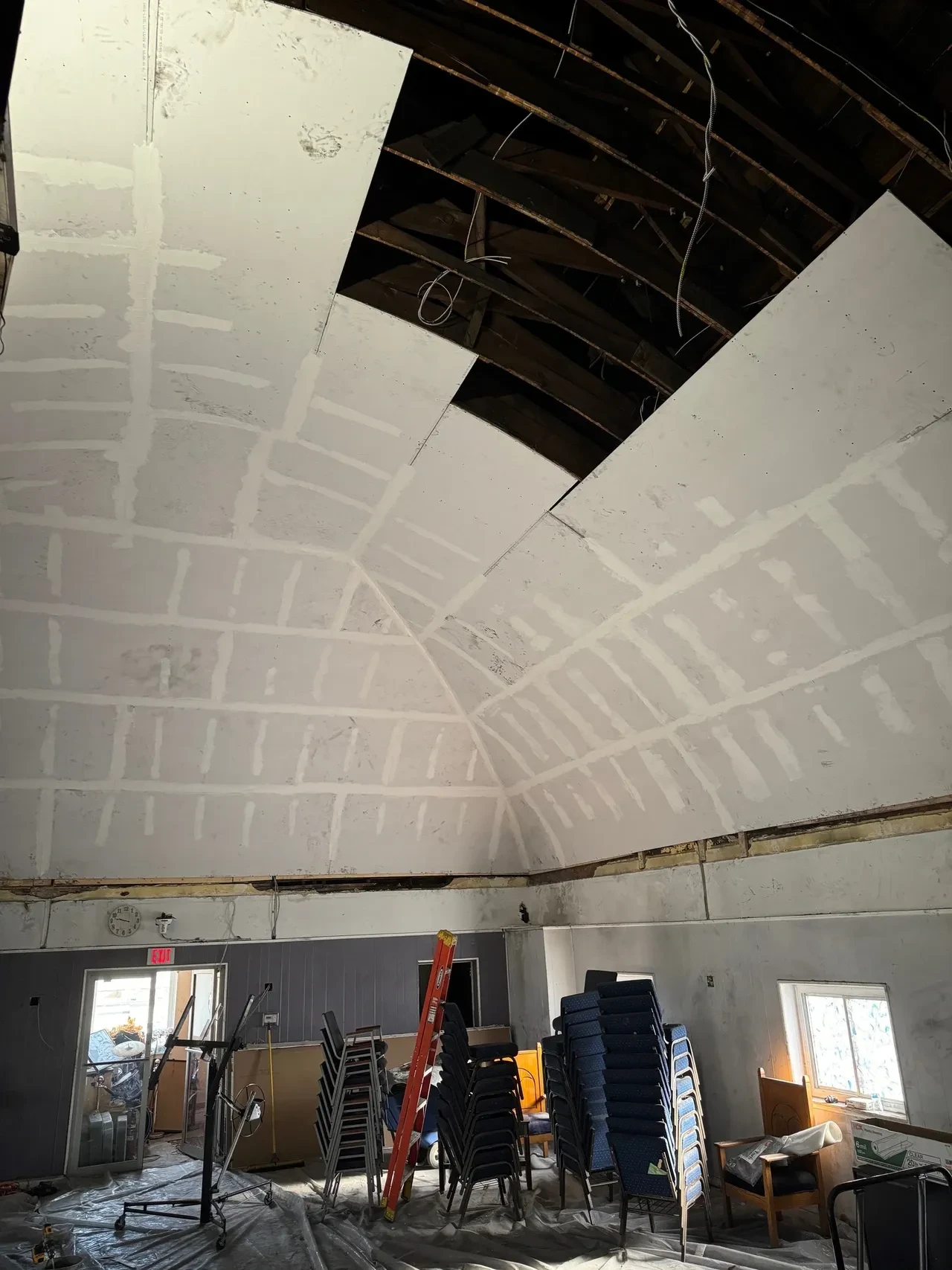 Church ceiling during restoration with new drywall installed over exposed rafters